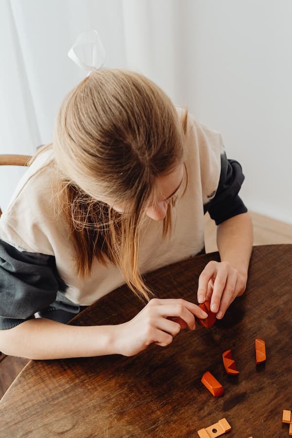 Une enfant assemble des pièces de jeu orange sur une table.