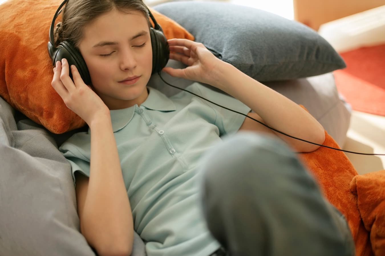 Une adolescente est allongée sur un canapé avec un casque audio.